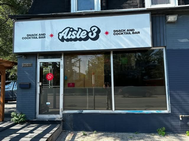 Refaced storefront sign panel on a blue-sided snack and cocktail bar