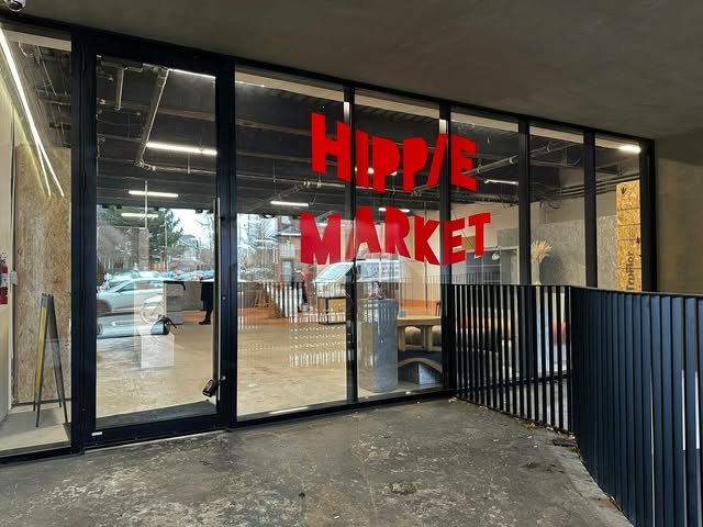 Large red HIPPIE MARKET window vinyl lettering on a glass storefront