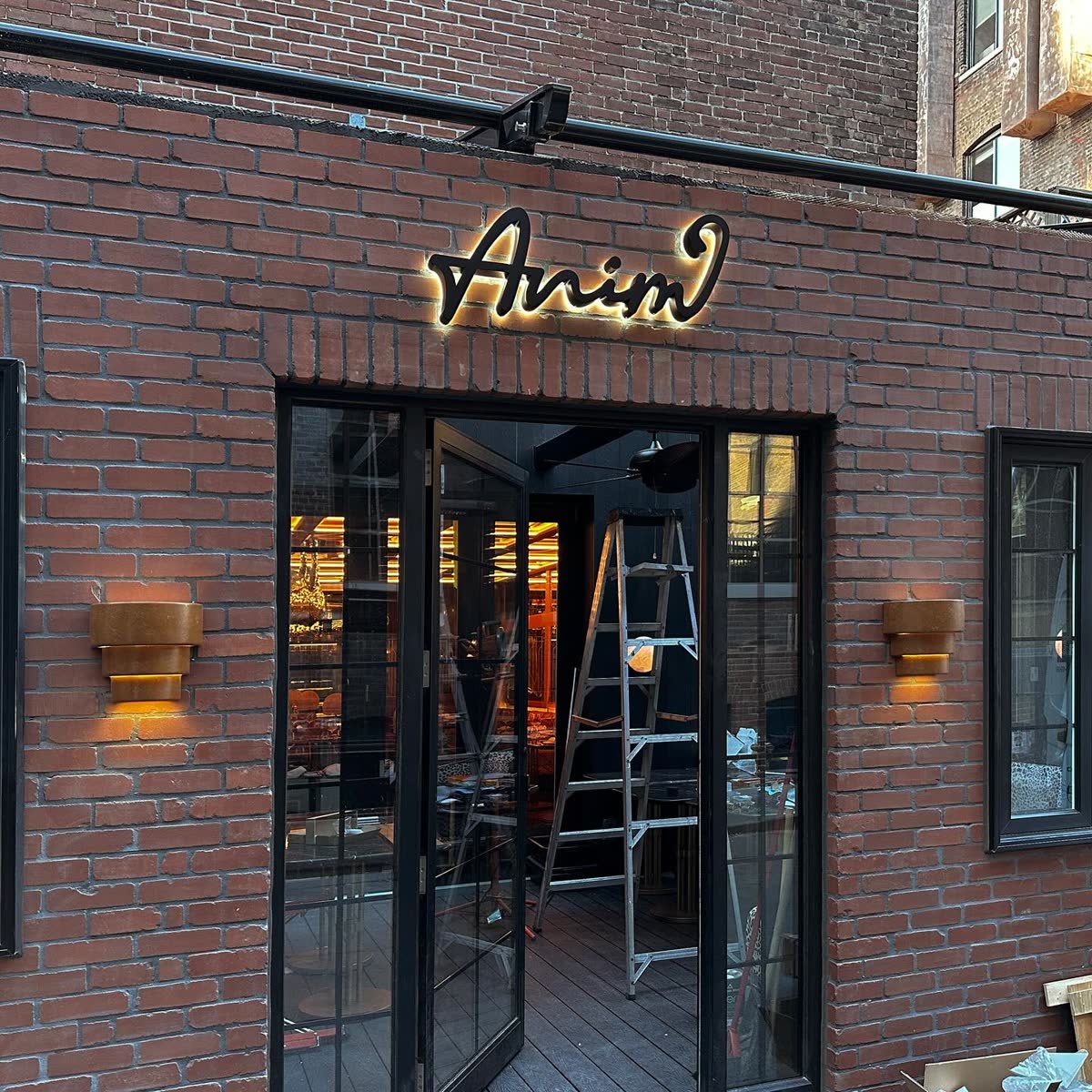Halo-lit script letters mounted on red brick above a restaurant entrance