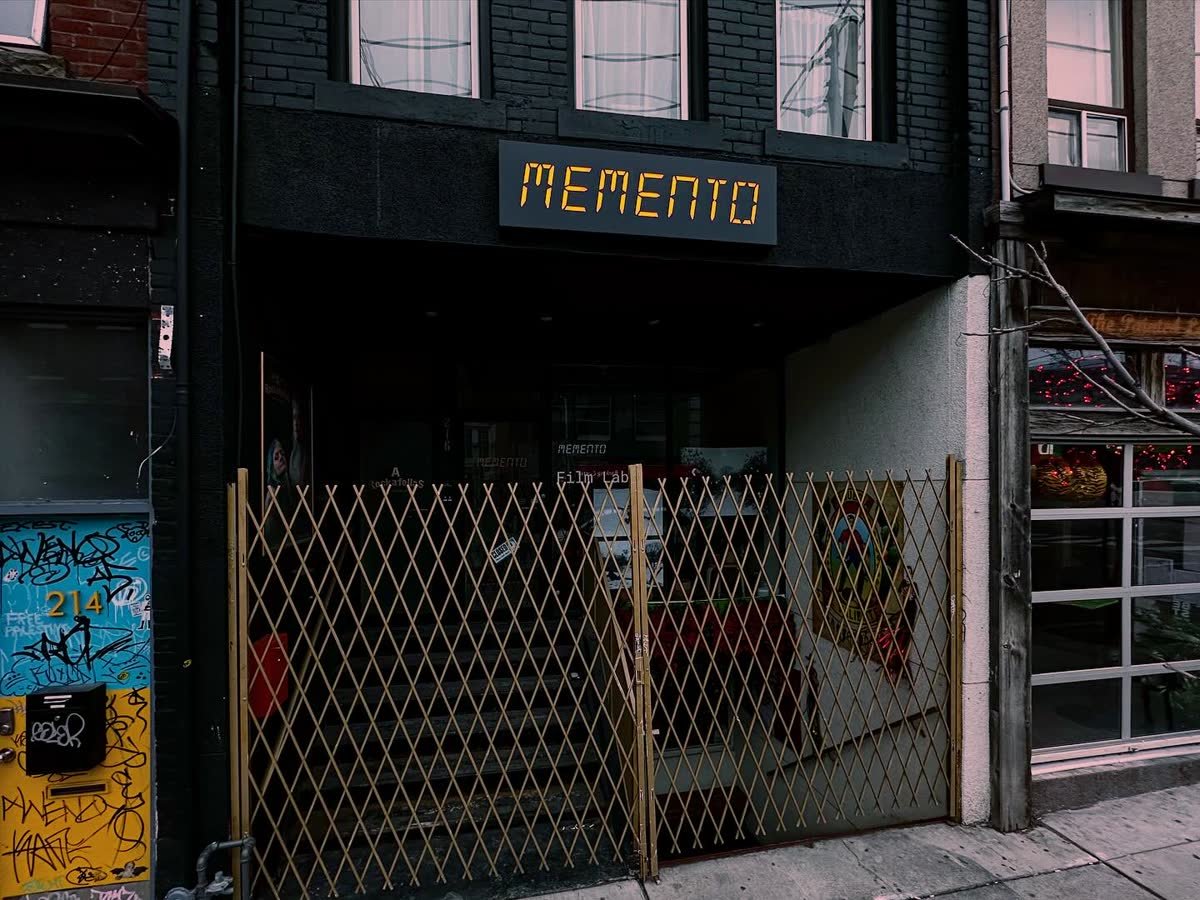 Illuminated storefront sign with orange lettering on a black facade