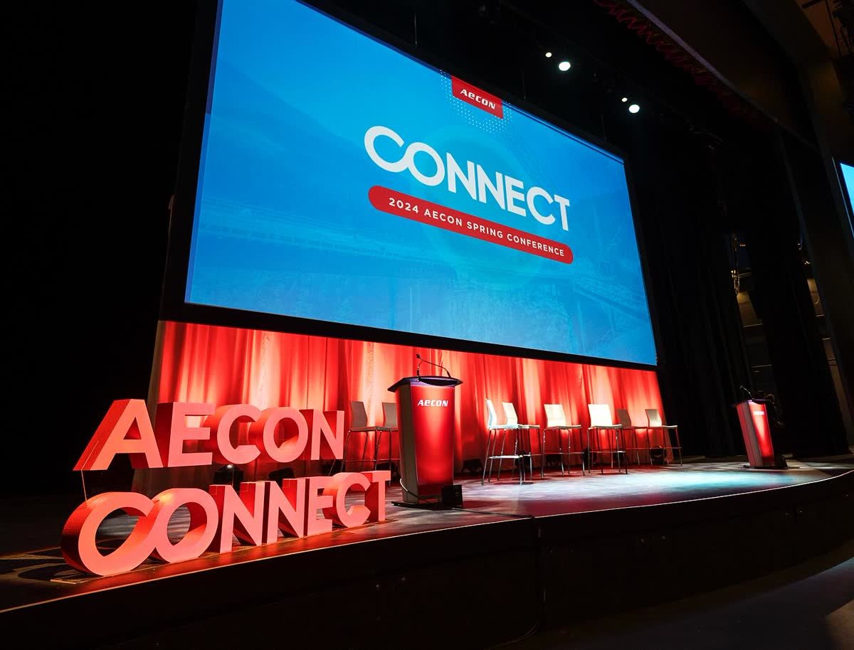 Conference stage with large red dimensional letters and screen graphics