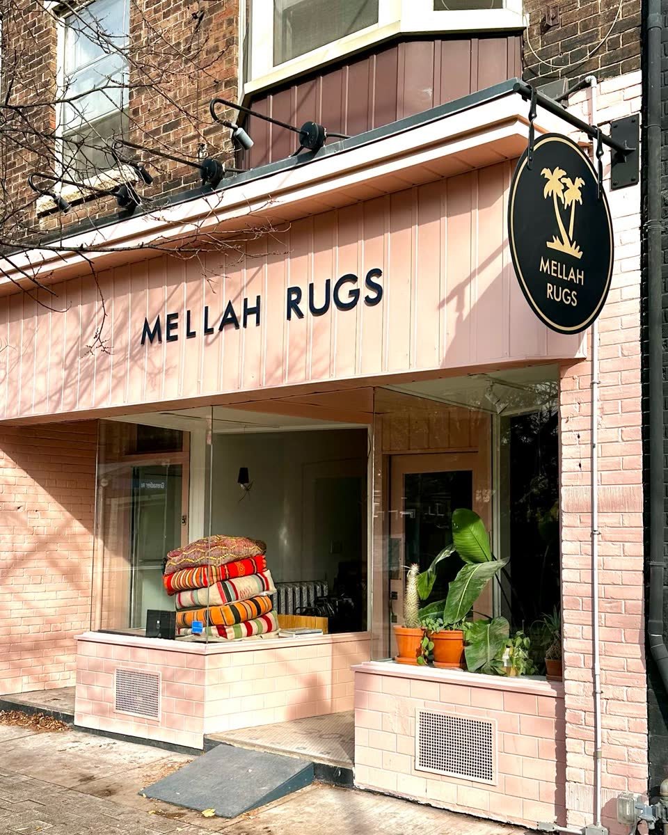 Round black and gold blade sign on a pink storefront