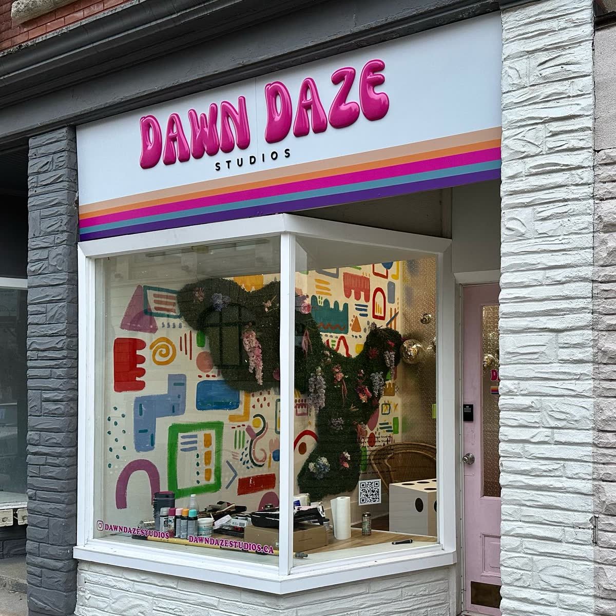 Colourful exterior sign with pink dimensional letters above a studio window