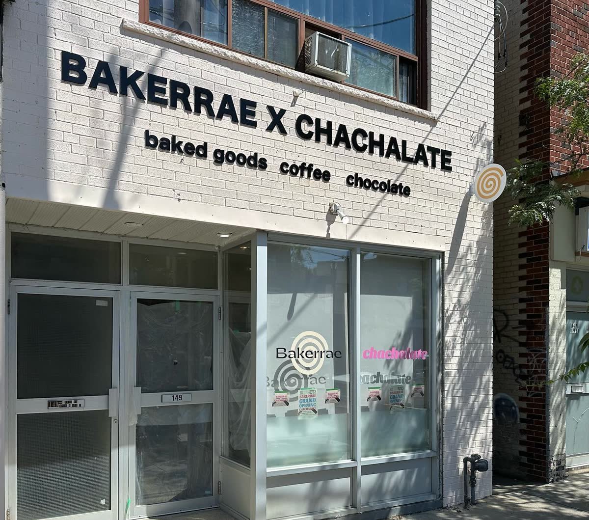 White brick cafe facade with black cut acrylic lettering and window graphics