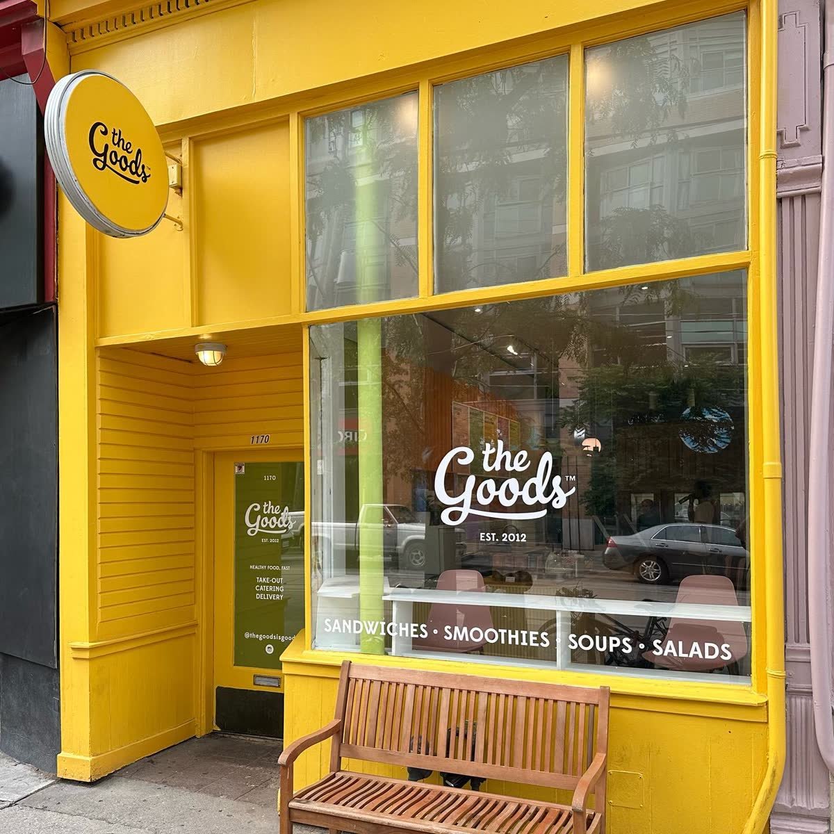 Yellow storefront with round blade sign and white window vinyl lettering
